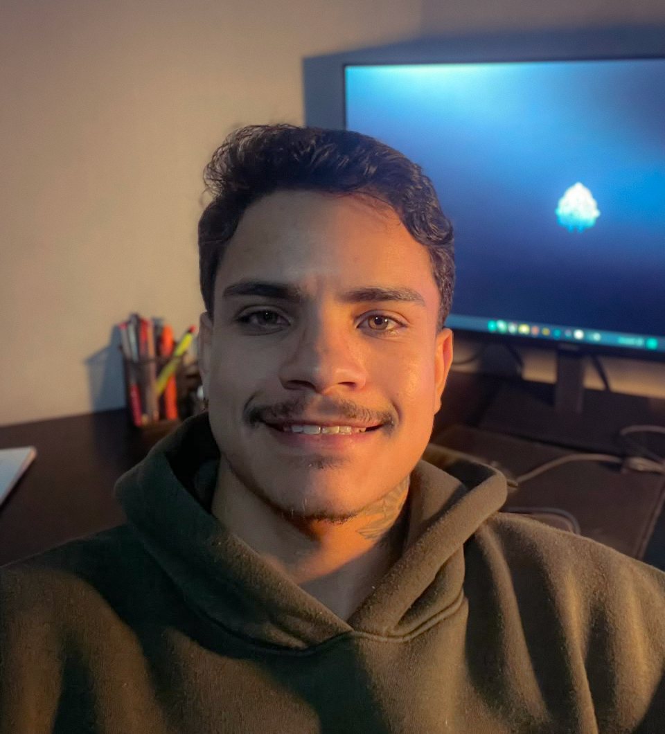Caio Ribeiro sorrindo em frente à mesa de trabalho